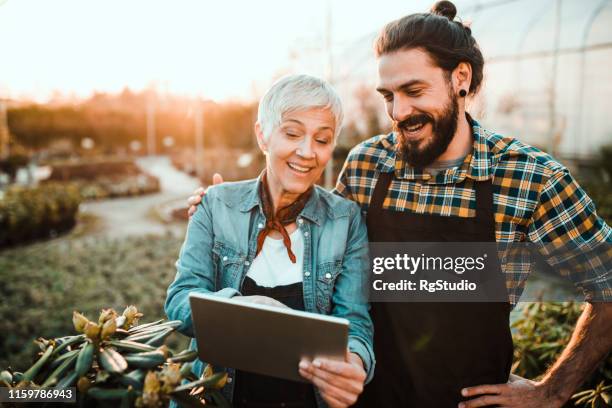 old woman and young man discussing in garden - father and son gardening stock pictures, royalty-free photos & images