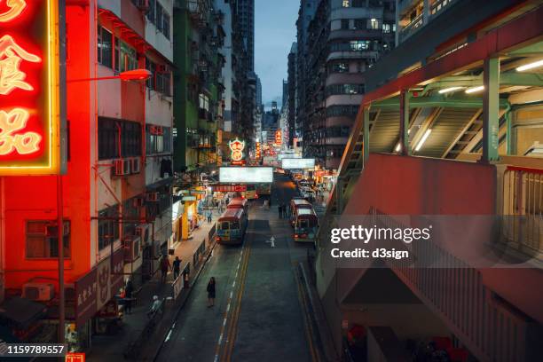 high density buildings with vibrant neon signs and bright street lights glowing along the busy city street in the crowded mongkok, china - mong kok imagens e fotografias de stock