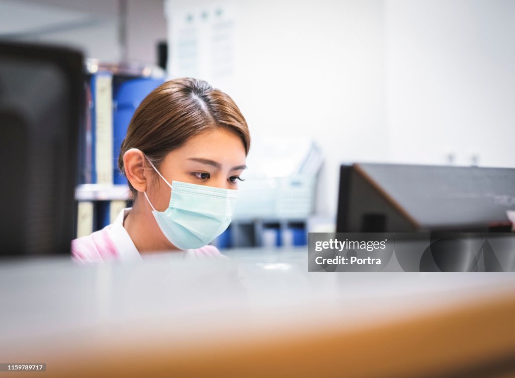 Serious nurse using computer in hospital