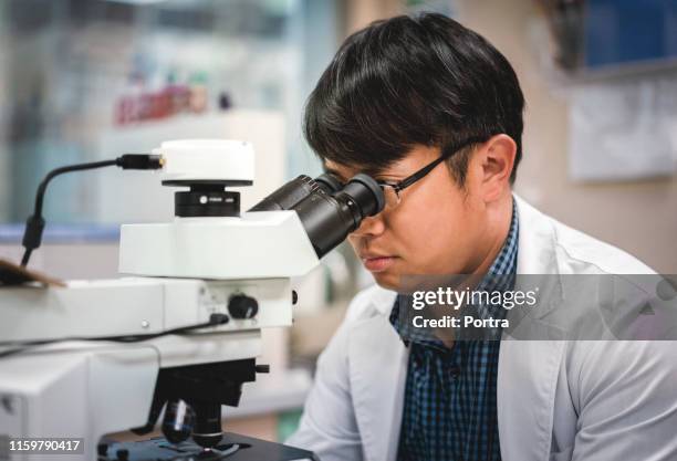 close-up of scientist looking through microscope - man microscope stock pictures, royalty-free photos & images
