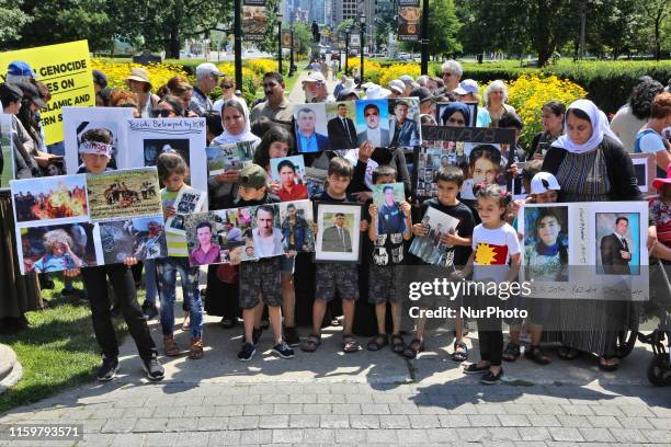 Yazidi children hold photos of family members killed by ISIS as members of the Yazidi ethnic community from Iraq who escaped death and persecution at...