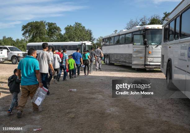 Immigrants walk to U.S. Homeland Security busses to be transferred to a U.S. Border Patrol facility in McAllen after crossing from Mexico on July 02,...