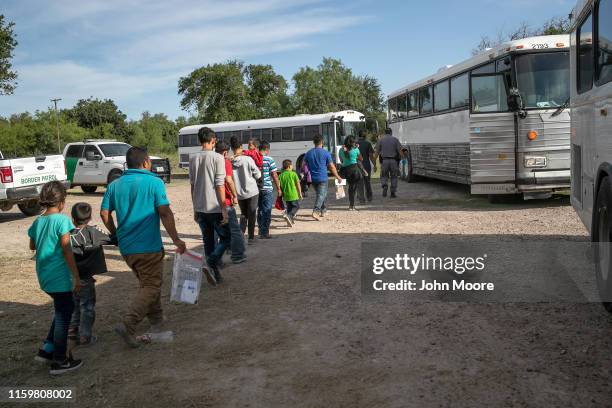 Immigrants walk to U.S. Homeland Security busses to be transferred to a U.S. Border Patrol facility in McAllen after crossing from Mexico on July 02,...