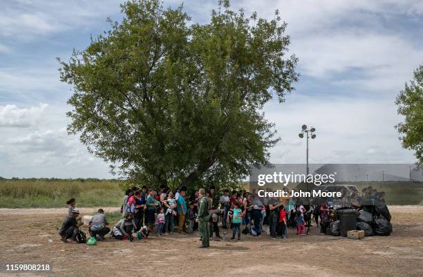 Immigrants wait in the shade after they were taken into custody by U.S. Border Patrol agents on July 02, 2019 in Los Ebanos, Texas. Hundreds of...