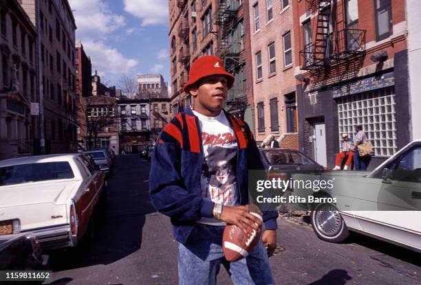 View of American rapper LL Cool J as ne holds a football as he stands in an unidentified street, New York, April 23, 1990.