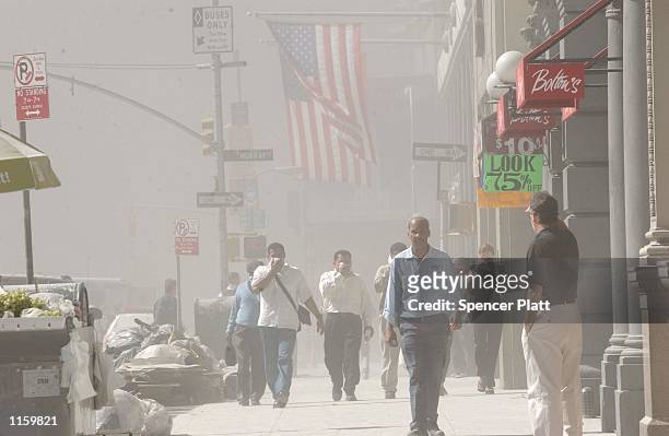 People rush away from the collapsing World Trade Center September 11, 2001 after two hijacked airplanes ran into the two towers in New York City in...