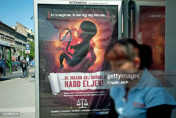 Woman waits in front of an anti-abortion poster bearing a picture of a foetus and slogan reading ''I can also understand if you are not yet prepared...