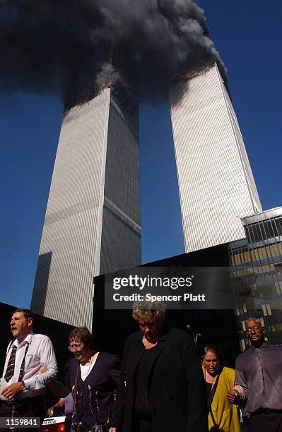 Civilians flee the area as a tower of the World Trade Center collapses September 11, 2001 in New York City after two airplanes slammed into the twin...