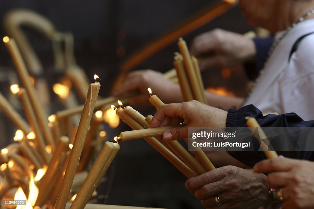 Multiple pairs of hands lighting gold candles