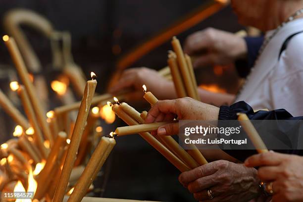 multiple pairs of hands lighting gold candles - fatima portugal stock pictures, royalty-free photos & images