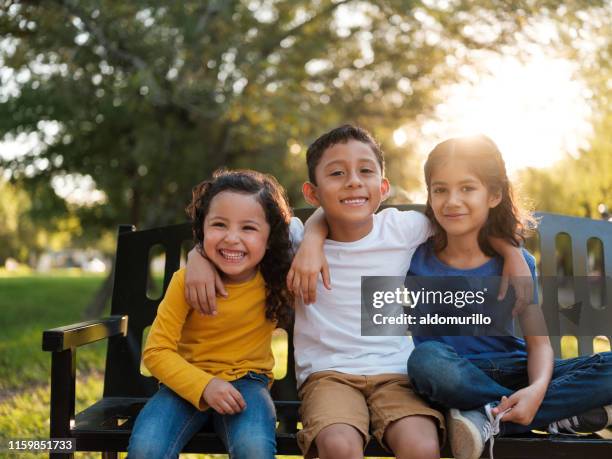 happy siblings side side by side in the park - latin american and hispanic stock pictures, royalty-free photos & images