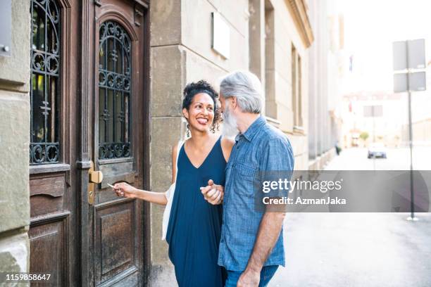 heterosexual mature couple opening the doors to their new apartment - cool couple in apartment stock pictures, royalty-free photos & images