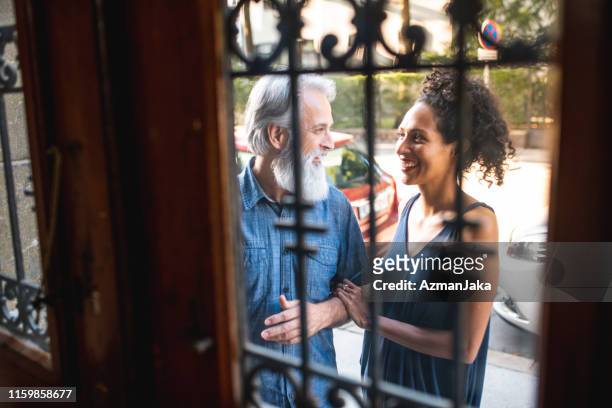 heterosexual mature couple opening the front doors to their new apartment - cool couple in apartment stock pictures, royalty-free photos & images