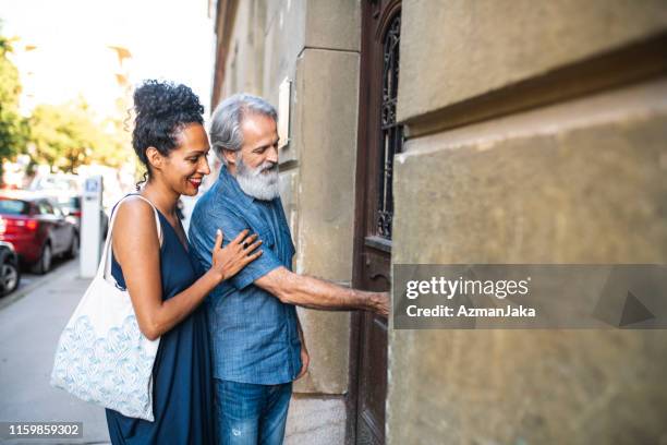 mature couple opening the doors to their new apartment - cool couple in apartment stock pictures, royalty-free photos & images