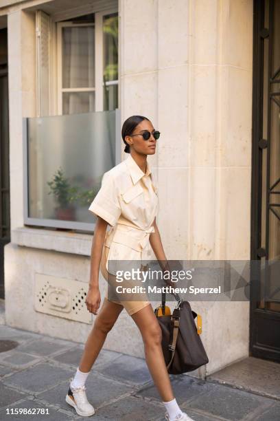 Guest is seen on the street during Paris Fashion Week Haute Couture wearing cream shirt and spandex biker shorts with white sneakers and black bag on...