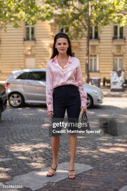 Guest is seen on the street during Paris Fashion Week Haute Couture wearing pink satin shirt with black shorts and heels on July 03, 2019 in Paris,...