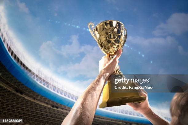atleet holding trophy cup boven het hoofd in het stadion - the championship voetbalcompetitie stockfoto's en -beelden