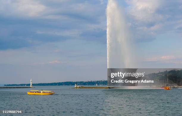 boat passing jet d'eau lake geneva, switzerland - lake geneva stock pictures, royalty-free photos & images