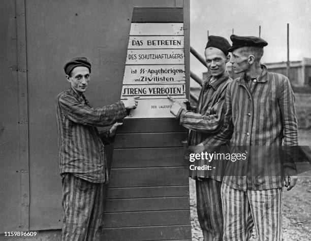 Picture taken on April 10, 1945 at Hanover-Harlen Nazi concentration camp, near Hanover, showing prisoners liberated pointing to a sign taken from...