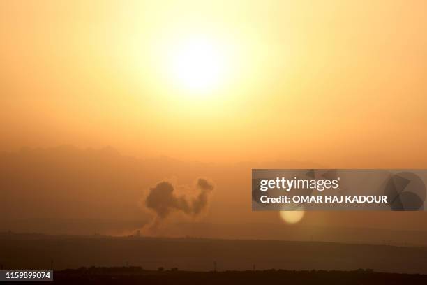 This picture taken on August 5, 2019 shows smoke billowing above buildings during a reported air strike by pro-regime forces on Khan Sheikhun in the...