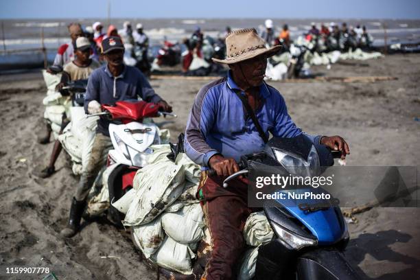 Workers wait in line to load sand affected by an oil spill at a shoreline onto a truck in Karawang, West Java, Indonesia, August 4, 2019. Indonesias...