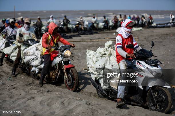 Workers wait in line to load sand affected by an oil spill at a shoreline onto a truck in Karawang, West Java, Indonesia, August 4, 2019. Indonesias...