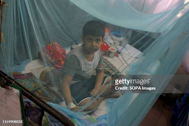 Kid infected with dengue fever receives treatment under a mosquito net at a hospital in Dhaka. A total of 27,437 people have been affected by dengue...