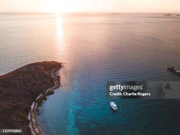 aerial photo of yacht and small island at sunset - papua new guinea beach stock pictures, royalty-free photos & images