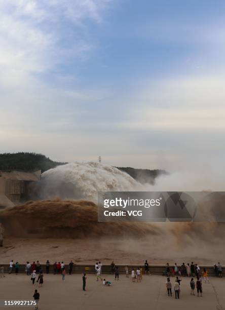 Tourists watch as water and sand is released from the floodgates of the Xiaolangdi dam on the Yellow River on July 3, 2019 in Jiyuan, Henan Province...