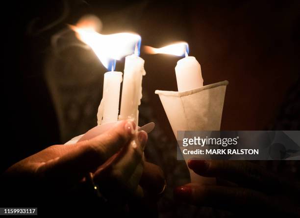 People hold candles as they pray during a candlelight vigil at the Immanuel Church for victims of a shooting that left a total of 22 people dead at...