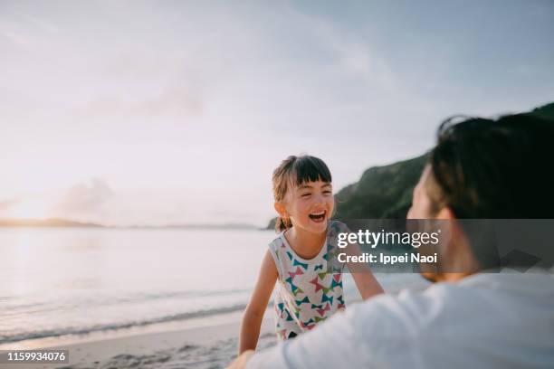 cute mixed race preschool girl laughing on beach at sunset, okinawa, japan - father sun stock pictures, royalty-free photos & images