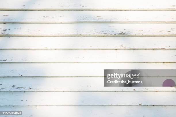 full frame shot of white painted, weathered wooden wall with shadow and sunlight - white wood stock pictures, royalty-free photos & images