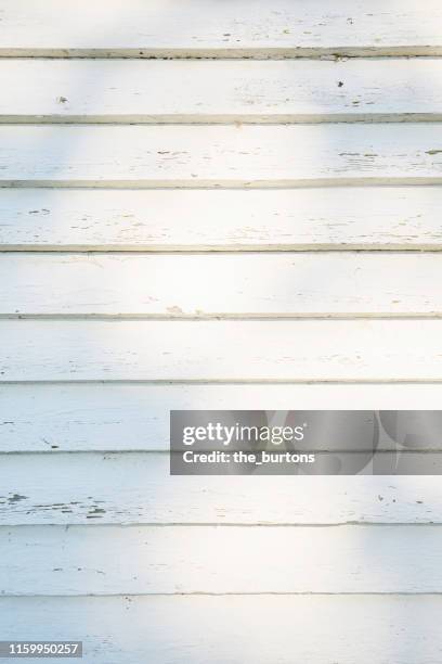 full frame shot of white painted, weathered wooden wall with shadow and sunlight - holzwand shabby chic stock-fotos und bilder