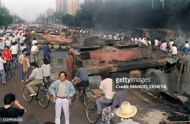 Beijing residents inspect the interior of one of over 20 armoured personnel carrier burnt by demonstrators to prevent the troops from moving into...