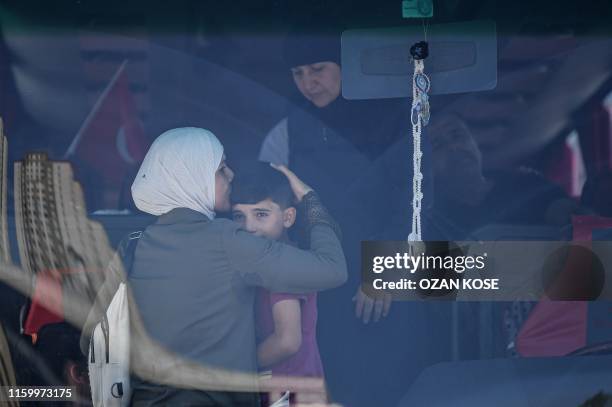 Syrian woman hugs a boy on a bus as Syrian refugees returning voluntarily to Syria prepare to leave on August 6,2019 in Esenyurt district in...