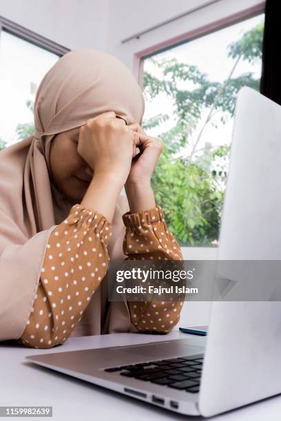 tired businesswoman with head in hand sitting at computer desk in office - fajrul islam stock pictures, royalty-free photos & images