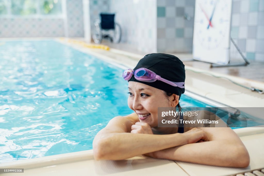 Paraplegic woman is resting inside a pool while training for competitive swimming