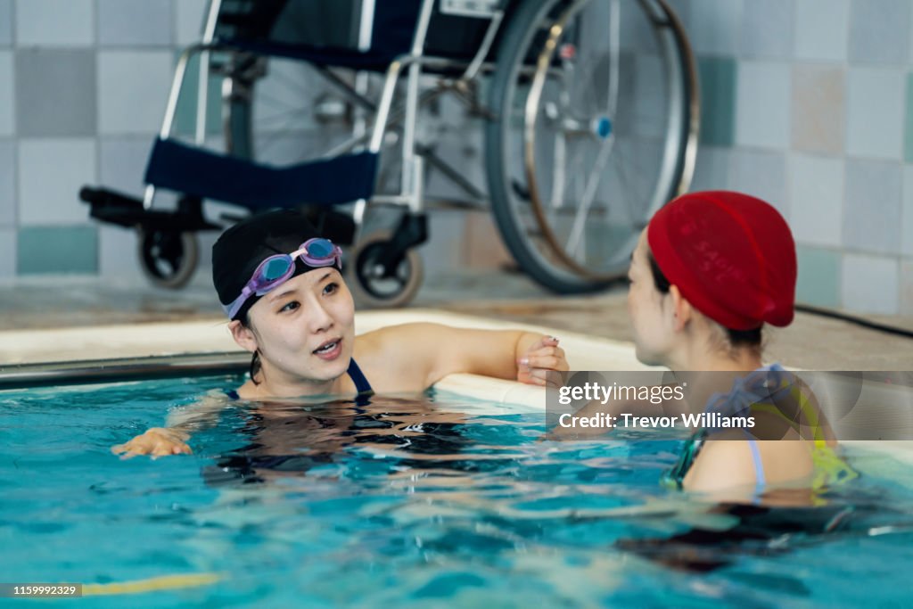 Disabled woman training for competitive swimming is listening to advice from her coach