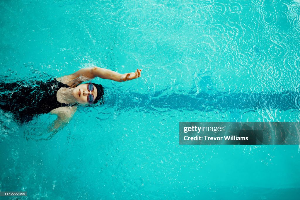 View from directly above a paraplegic woman training in a pool for competitive swimming.