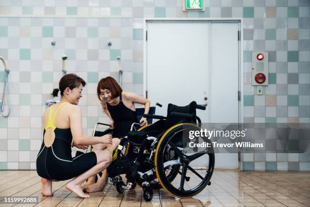 paraplegic woman switching wheelchairs with coach before or after training for competitive swimming - wheelchair ramp stock pictures, royalty-free photos & images