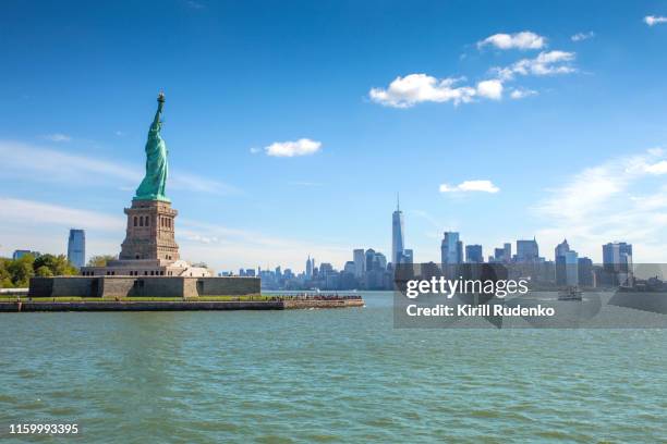 liberty island and the statue of liberty with the lower manhattan in background - statue of liberty new york city fotografías e imágenes de stock