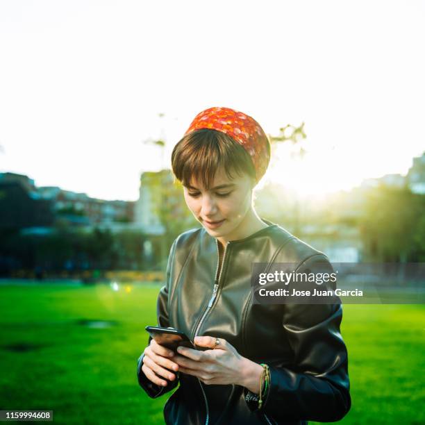 jeune femme gai utilisant le téléphone dans un stationnement - europe de l'ouest photos et images de collection