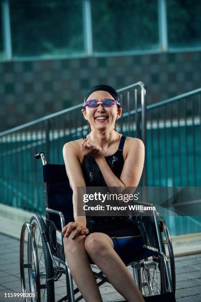 portrait of a paraplegic woman in a wheelchair next to a pool after training for competitive swimming - paraplegic stock pictures, royalty-free photos & images