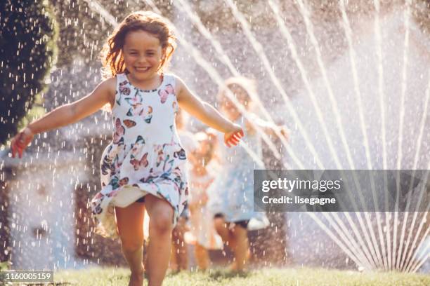 bambini felici che giocano con l'irrigatore da giardino - annaffiatore foto e immagini stock