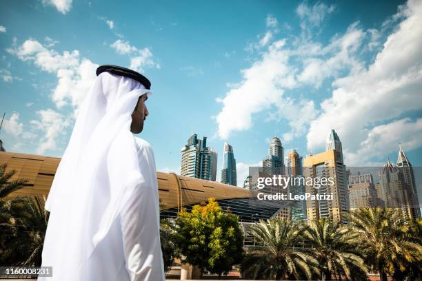 scheich mit blick auf wolkenkratzer und bürogebäude in der innenstadt von dubai - emirati business stock-fotos und bilder