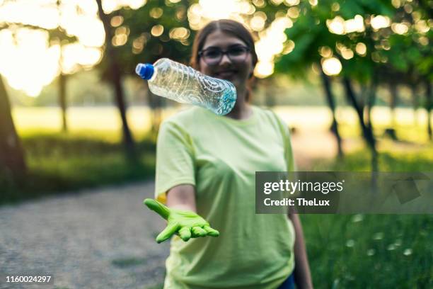 millennial volunteer girl with a plastic bottle - park service stock pictures, royalty-free photos & images