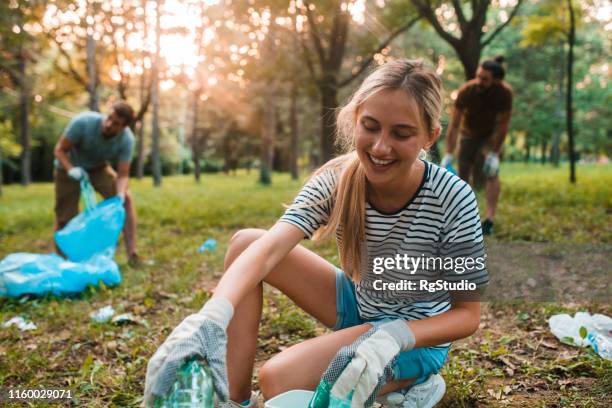 junge frau recycelt flaschen - charity education stock-fotos und bilder