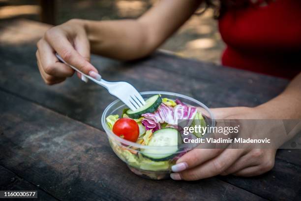 girls seating on the bench and eat salad - plastic cutlery stock pictures, royalty-free photos & images