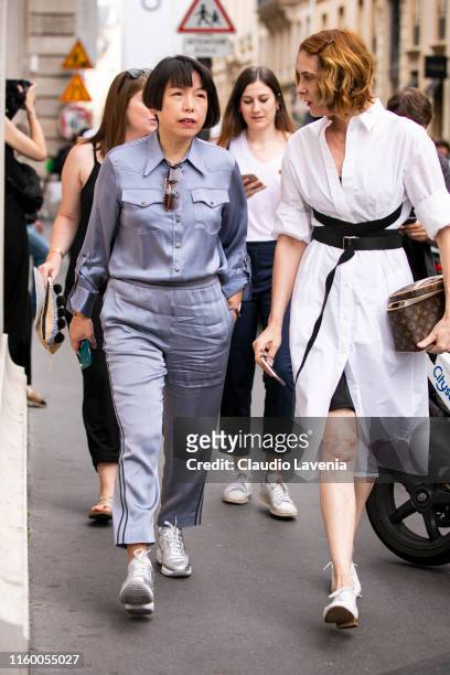 Angelica Cheung , wearing a grey silky shirt with matching pants and silver shoes, and a guest , wearing a white shirt dress, black belt, white shoes...