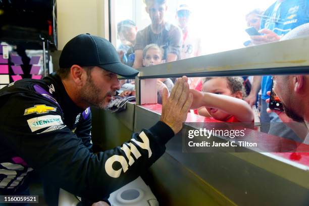 Jimmie Johnson, driver of the Ally Chevrolet, signs autographs for fans in the garage area during practice for the Monster Energy NASCAR Cup Series...
